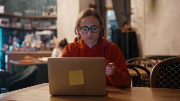 Kafe 'de dizüstü bilgisayarda çalışan beyaz bir kadın ya da blogcu. Teknoloji kullanan üniversite öğrencisi, çevrimiçi eğitim, serbest çalışma. — Stok video