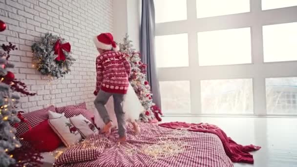 Lindos niños saltando en la cama con almohada, Navidad por la mañana, fiesta de niños. La Navidad trae tanta diversión. — Vídeos de Stock