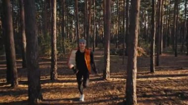 Gündoğumunda sonbahar ormanında koşan genç bir kadın. Yavaş çekim 4k