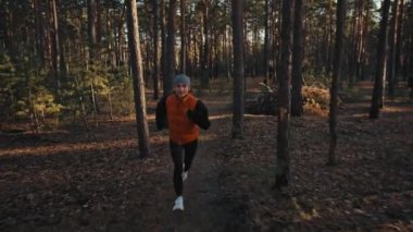 Gündoğumunda sonbahar ormanında koşan genç bir kadın. Yavaş çekim 4k