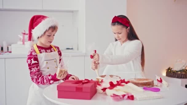 Feliz niña y niño haciendo pastel casero para Navidad en el interior de la casa de luz. Preparación de Navidad — Vídeo de stock