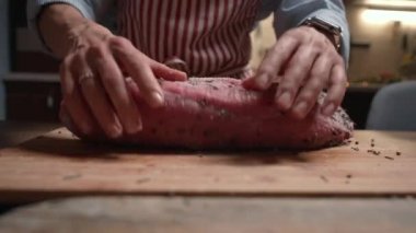 Aşçı kadın bifteğe yağ ve baharat döküyor. Üst düzey gıda hazırlama süreci konsepti. Biftek..