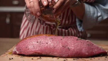 Aşçı kadın bifteğe yağ ve baharat döküyor. Üst düzey gıda hazırlama süreci konsepti. Biftek..