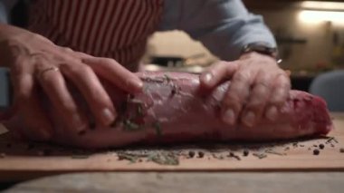 Aşçı kadın bifteğe yağ ve baharat döküyor. Üst düzey gıda hazırlama süreci konsepti. Biftek..