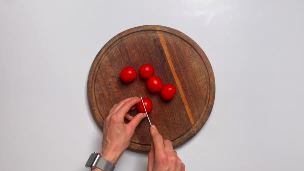 Unknown woman holding a knife in her hands and cutting tomatoes while cooking vegetable salad near kitchen table ,close up — Stock Video