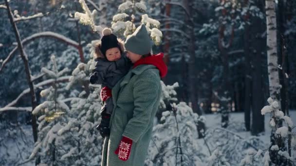 Joven madre feliz divirtiéndose y jugando con su hijo pequeño en el bosque nevado en invierno — Vídeos de Stock