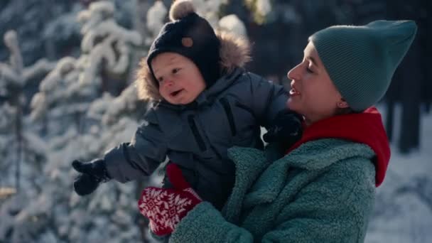 Ung lycklig mor som har roligt och leker med småbarn son i snöig skog på vintern — Stockvideo