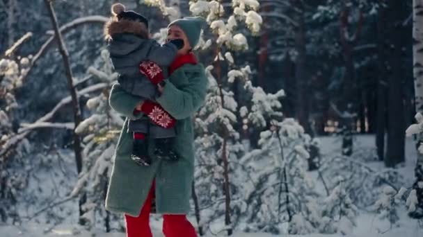 Young happy mother having fun and playing with toddler son in snowy forest in winter — Stockvideo