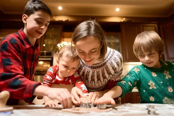 Cute children making cookies with mother on Christmas Day at home — стоковое фото
