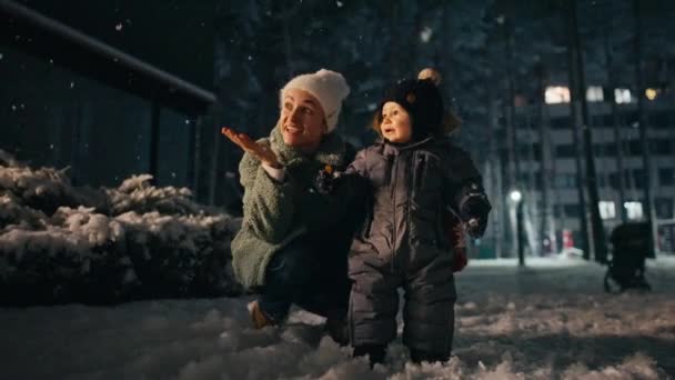 Mother and son playing at winter festival, snowing. — Stok video
