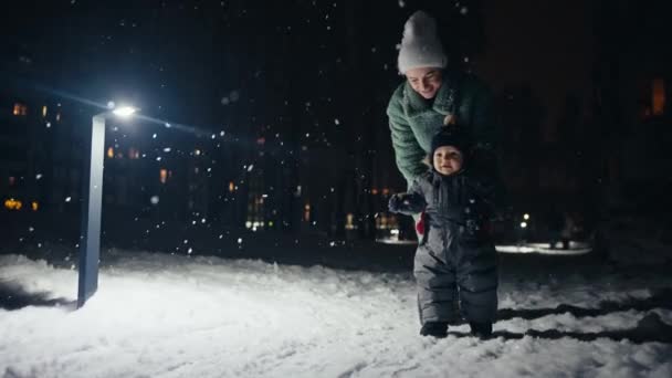 Mother and son playing at winter festival, snowing. — Stockvideo