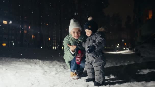 Madre e hijo tocando en el festival de invierno, nevando. — Vídeos de Stock