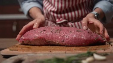 Aşçı kadın bifteğe yağ ve baharat döküyor. Üst düzey gıda hazırlama süreci konsepti. Biftek..