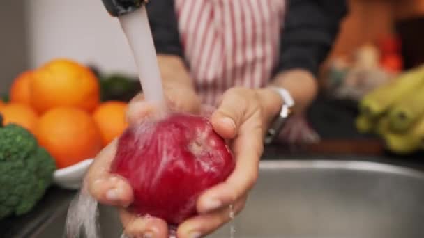 Las manos femeninas lavan la manzana bajo el agua en el fregadero. Lavarse las manzanas rojas en las manos de las mujeres — Vídeos de Stock