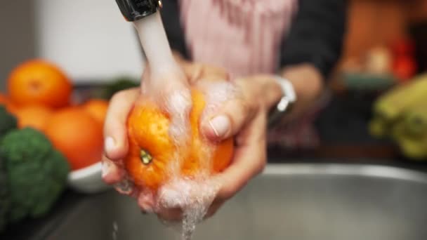 Samice myją świeżą pomarańczę strumieniem wody. Zamknij drzwi. Ujęcie w zwolnionym tempie. — Wideo stockowe