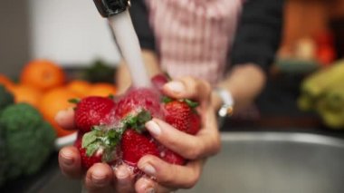 Kadın elleri mutfakta çilek yıkıyor. Yavaş çekim..