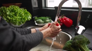 Mutfaktaki su deresinin altında domates yıkayan kadın elleri. Yavaş çekim.