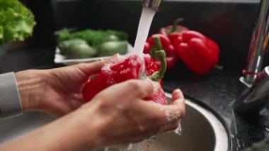 Musluk suyunun altında kırmızı biber yıkayan kadın, ağır çekim 4K