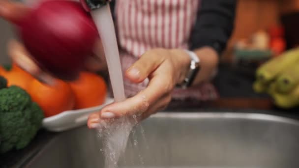 Női kézmosás alma víz alatt mosogató. A vörös almát női kézben mossa, lassított felvétel — Stock videók