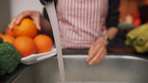 女性の手は水の流れによって新鮮なオレンジを洗っている。閉じろ!. — ストック動画