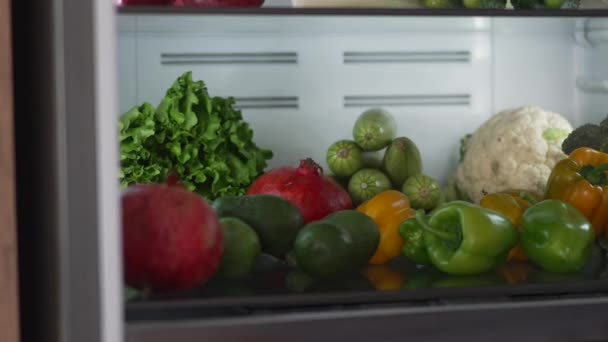 Mulher a tirar comida crua do frigorífico. Frigorífico cheio de comida saudável. frutos e produtos hortícolas. — Vídeo de Stock