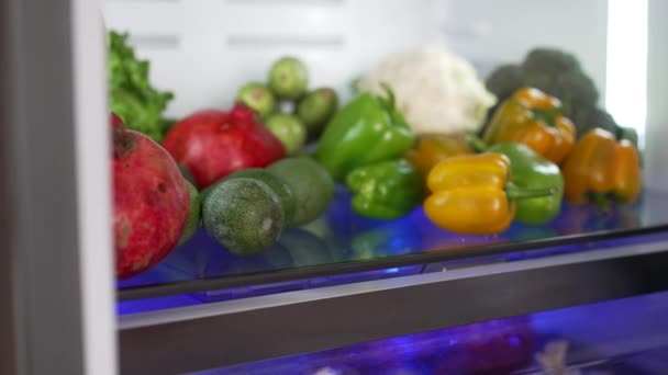 Frauen nehmen Lebensmittel aus dem Kühlschrank. Frau nimmt Avocado. — Stockvideo