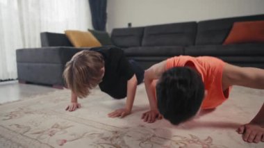 İki erkek kardeş evdeki parlak mutfakta spor yapıyor. Ev antrenmanı. Evde kal. Aile kavramı. İki çocuk şınav çekiyor.