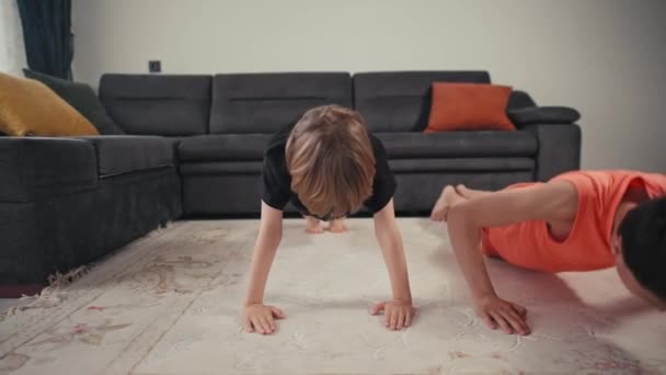 Zwei Jungen-Brüder treiben zu Hause in der hellen Küche Sport. Heimtraining. Bleiben Sie zu Hause. Familienkonzept: Zwei Jungen machen Liegestütze — Stockvideo