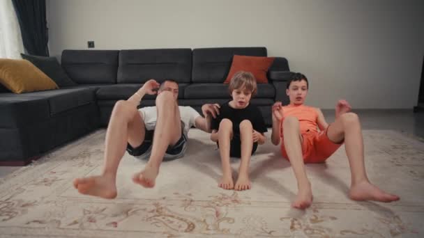 Padre con hijos haciendo ejercicio en casa. Padre y dos hijos haciendo deportes en la alfombra en la sala de estar en casa — Vídeos de Stock