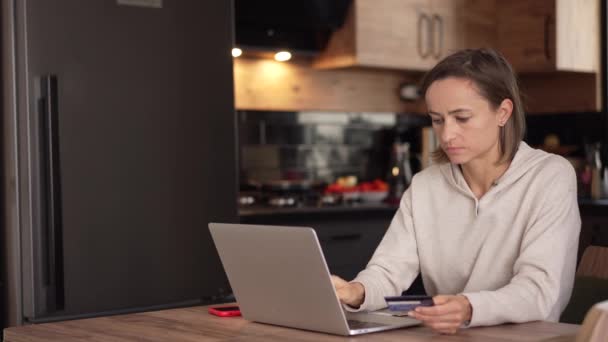 Caucasian woman makes an online payment using a bank card and laptop — Stock Video