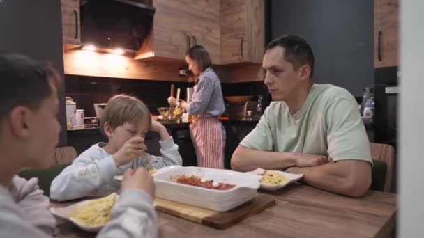 Jovem família feliz conversando enquanto janta na mesa de casa — Vídeo de Stock