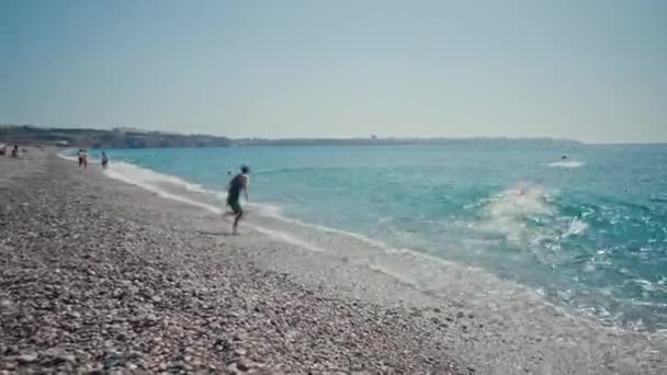 Tiro de entrenamiento de triatlón en la orilla del mar por la mañana. Un grupo de jóvenes atletas invade el agua. Empieza a nadar en el mar o en el océano — Vídeos de Stock
