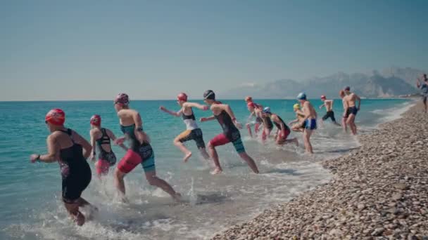 ANTALYA, TURKEY APRIL 15, 2022: Ditembak Triathlon pelatihan di pantai laut di pagi hari. Sekelompok atlet muda menyerang air. Mulai berenang di laut atau laut — Stok Video