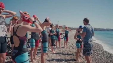 ANTALYA, TURKEY - 15 Nisan 2022: sabah deniz kıyısında Triatlon eğitimi. Suyun kenarında bir grup genç sporcu. Denizde ya da okyanusta yüzmeye başla.