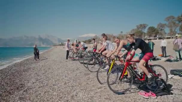 ANTALYA, TURQUÍA - 15 DE ABRIL DE 2022: Tiro de entrenamiento de triatlón en la orilla del mar por la mañana. Un grupo de jóvenes atletas entrenan en el ciclismo — Vídeos de Stock