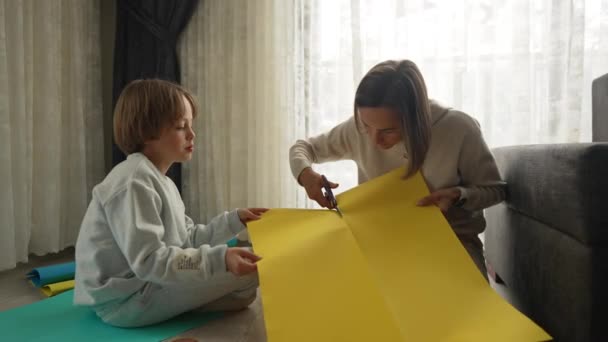 Moeder en zoon maken Oekraïense vlag. Protest tegen de oorlog nadat Rusland de invasie van Oekraïne was begonnen — Stockvideo