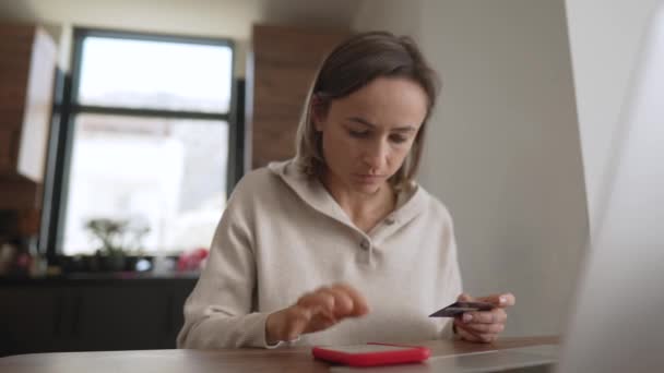 Irritated young caucasian girl sitting with computer and credit card on couch in kitchen room, can not make purchase, not enough money. Unhappy client dissatisfied with online payment banking service — Stock Video