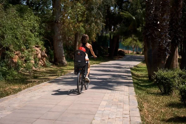 Küçük oğluyla bisiklete binen genç bir kadın.