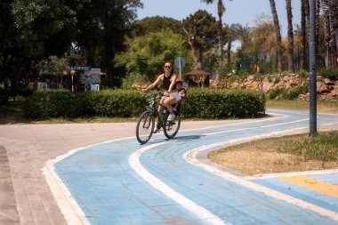 Küçük oğluyla bisiklete binen genç bir kadın.