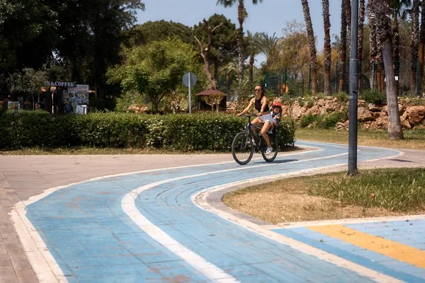 Küçük oğluyla bisiklete binen genç bir kadın.