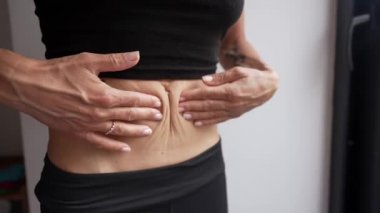 Ellerini sıska kadının karnına koy. Kadın hamilelikten sonra karnını kontrol ediyor.