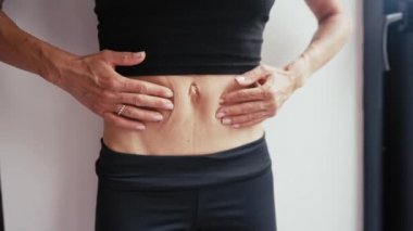 Ellerini sıska kadının karnına koy. Kadın hamilelikten sonra karnını kontrol ediyor.