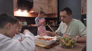 Evde yemek yerken genç mutlu aile sohbeti.