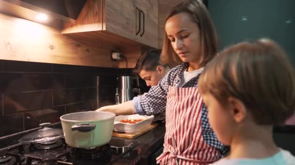 Madre e hijo caucásicos preparando la cena juntos en casa. Lindo chico ayudando a sus padres mientras que la mujer feliz en la cocina doméstica. Relaciones familiares. — Vídeos de Stock