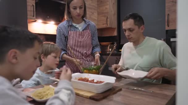 Jovem família feliz conversando enquanto janta na mesa de casa — Vídeo de Stock