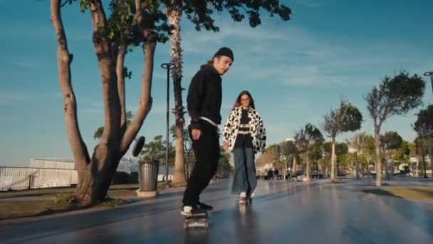 ヒップスターカップルスケートボード。若いカップルのスケートボードの通りです。ビーチでスケートボードを楽しんでいるカップル — ストック動画