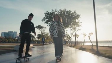 Hipster couple skateboarding. Young couple skateboarding in the street. Couple having fun with skateboard on beach