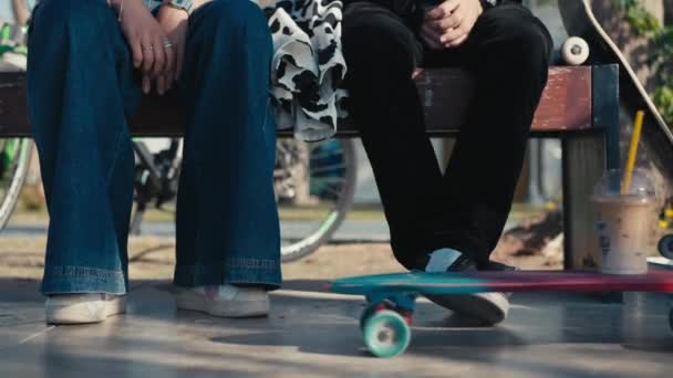 A couple of young people skateboarders paused to drink coffee. A glass of ice latte rides up on a skateboard. Concept of lifestyle, vintage, friendship. High quality 4k footage. — Stockvideo