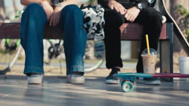 A couple of young people skateboarders paused to drink coffee. Two cups of coffee ride up on a skateboard. Concept of lifestyle, vintage, friendship. High quality 4k footage. — Vídeo de Stock