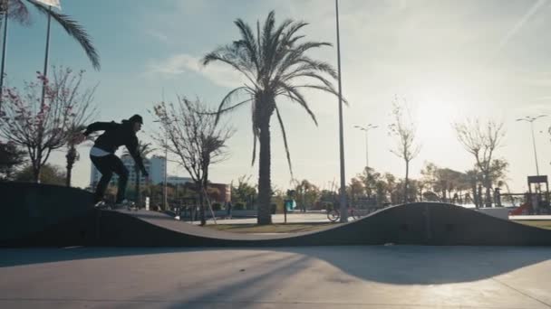 Skateboarder em um parque de atletismo. Skateboarder praticar em um parque de pista bomba em um dia ensolarado de verão — Vídeo de Stock